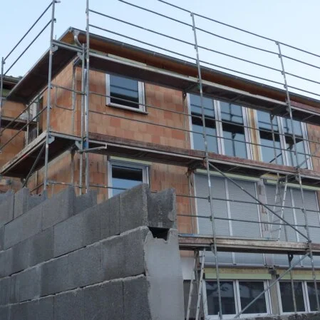 Eingerüstetes Haus ohne Fassadenputz fertig zur Rohbauinstallation